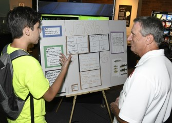 Kevin Fratostitanu, from Manlius Pebble Hill School, discusses findings about fish with Honeywell Syracuse Program Manager Stephen Miller on Discovery Day at the MOST.